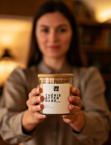 Person holding a candle labeled 'Chérie' in a warm indoor setting