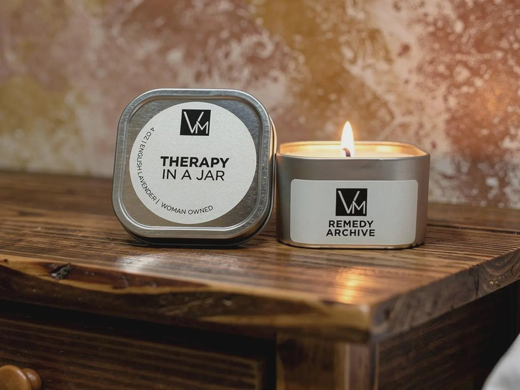 Candle labeled 'Therapy in a Jar' by Remedy Archive on a wooden surface with a blurred background.